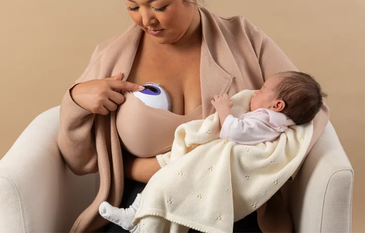 Person pressing the controls of a Lansinoh DiscreetDuo Flow worn inside a bra