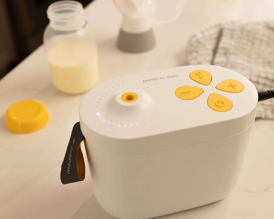 Medela Pump In Style Pro motor on a counter beside a milk bottle.