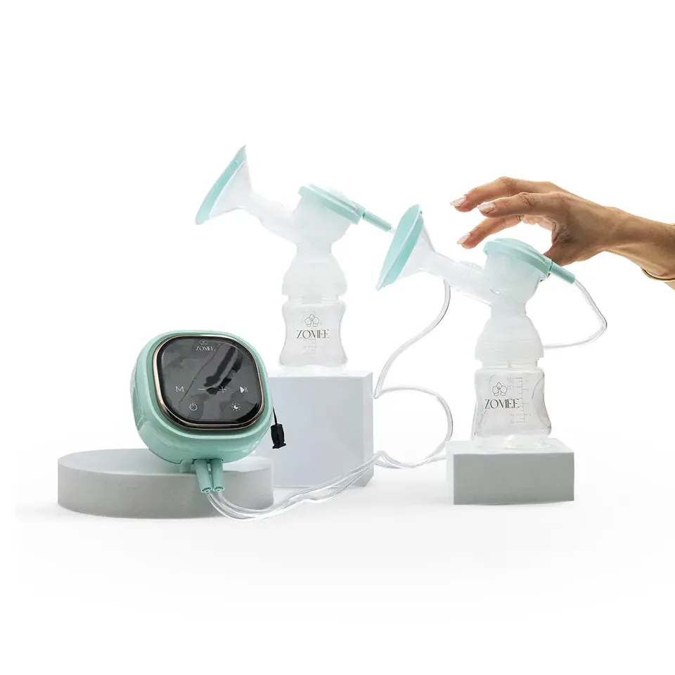 Hand reaching toward a Zomee Z2 collection bottle beside the motor